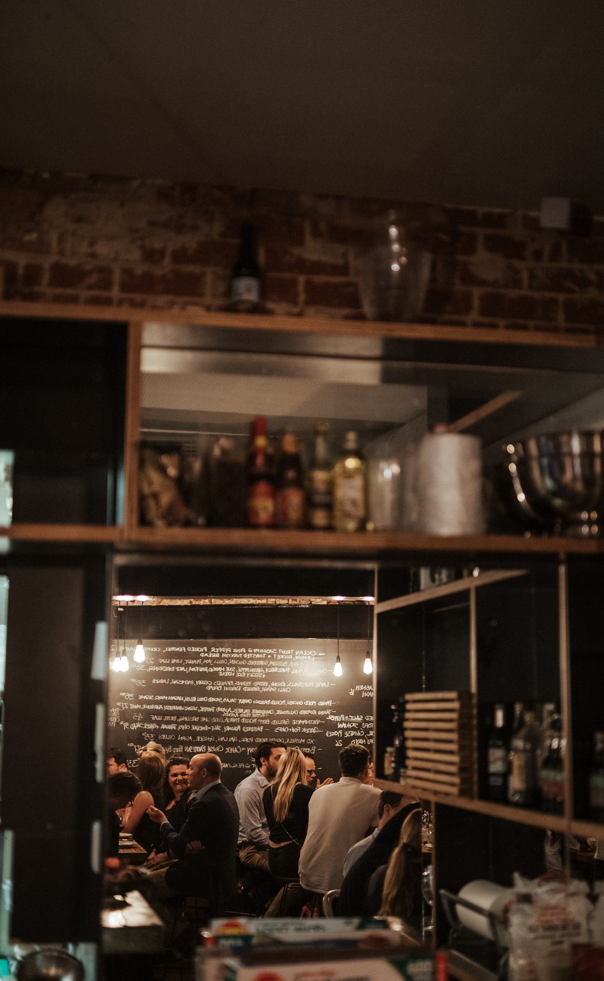 A warm, candlelit brick dining room, the table full and mid-conversation